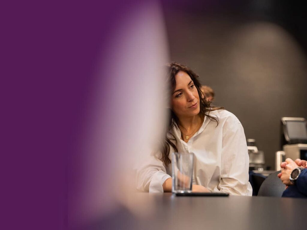 Woman sitting at desk talking to a man out of shot